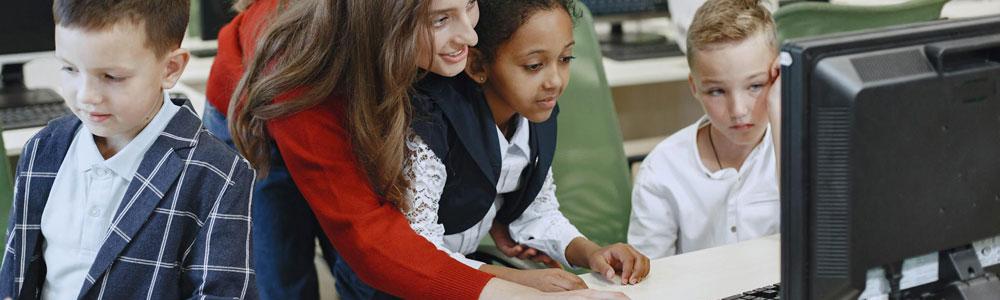Teacher helping students with computers