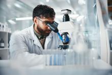 Male doctor looking through a microscope in a lab.
