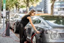 Woman charging electric car at the side of the road