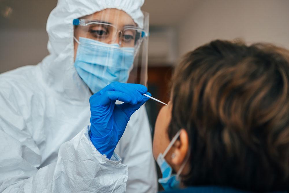 Woman in PPE giving a COVID-19 test to a woman